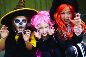Portrait of three Halloween girls looking at camera with frightening gesture